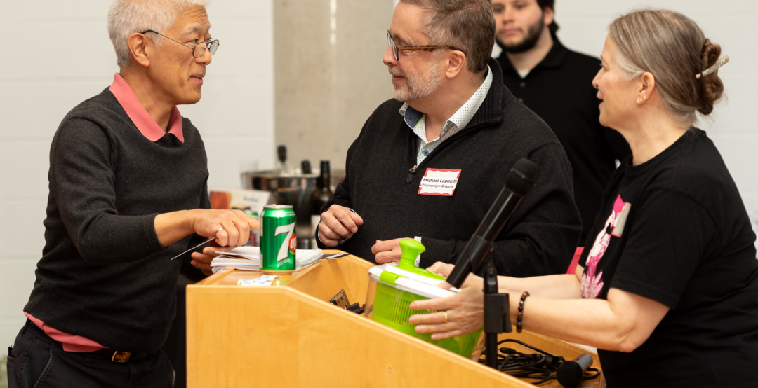 Lester Hiraki wins a draw prize with Michael Lapointe VP Campaigns and Equity and Catherine Jenkins President